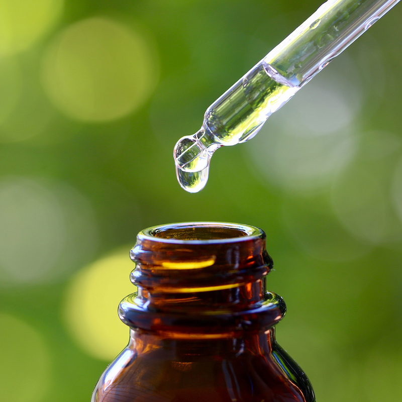 dropper with liquid in it over an open bottle